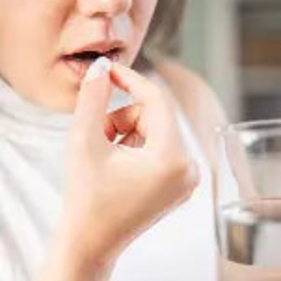 Kvinne som tar Herba Plus B-Comp Forte tablett med glass vann – daglig inntak av B-vitaminkompleks for normal energiomsetning og nervesystemets funksjon