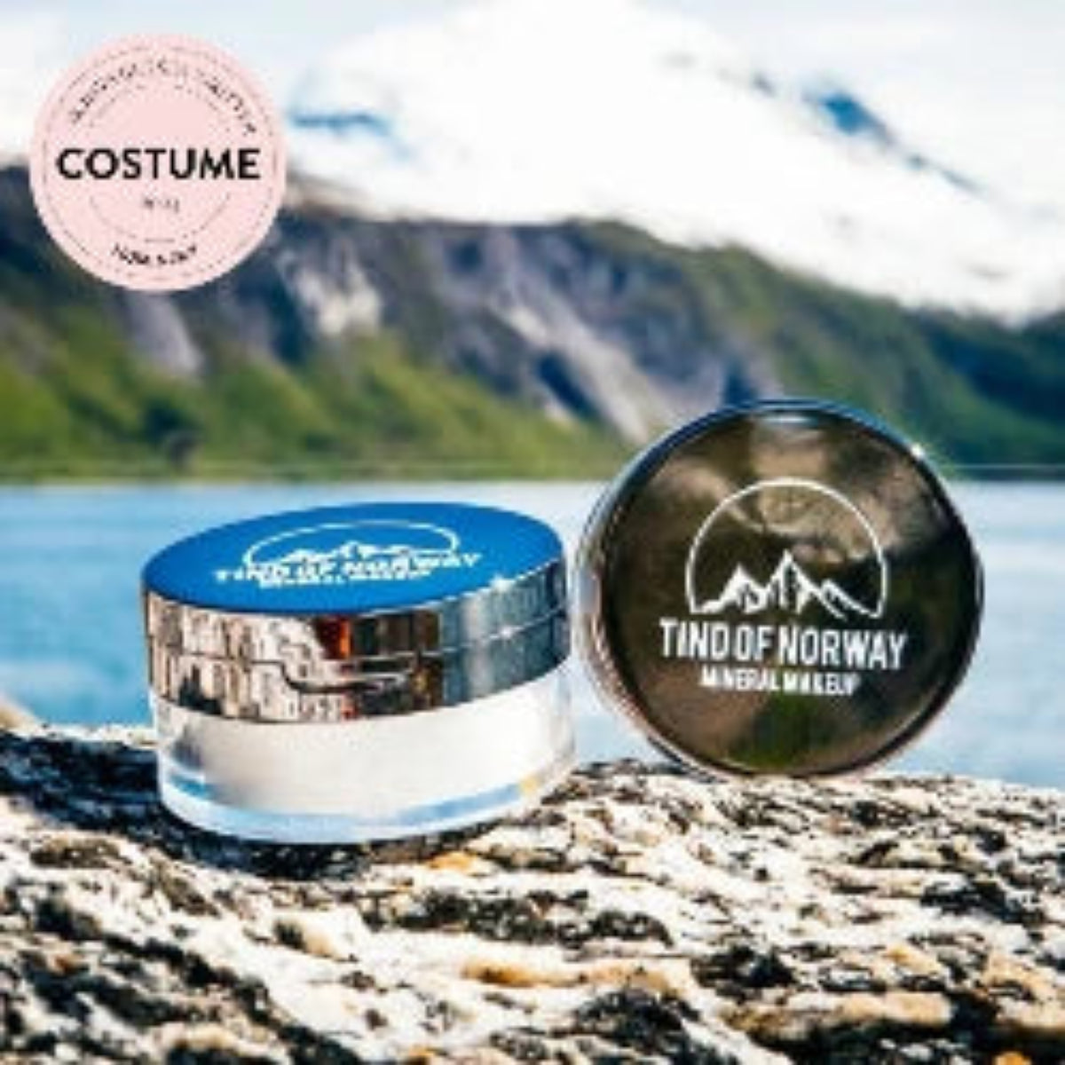 Tind of Norway pudderboks på stein foran fjell og vann, med Costume-merke øverst
