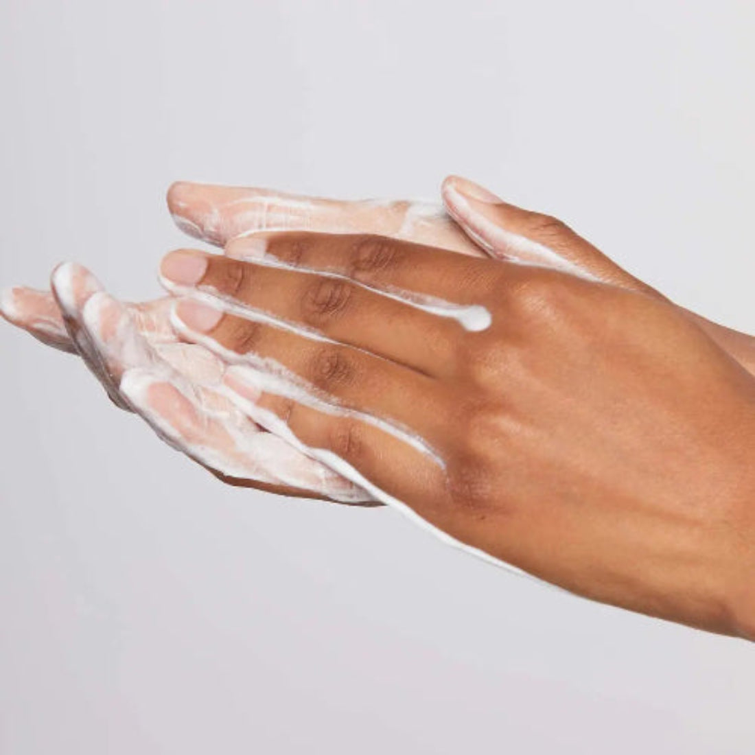 Hånd som gnir aktivert Dermalogica Daily Microfoliant mellom håndflatene – risbasert peelingpulver blandet med vann for skånsom daglig eksfoliering