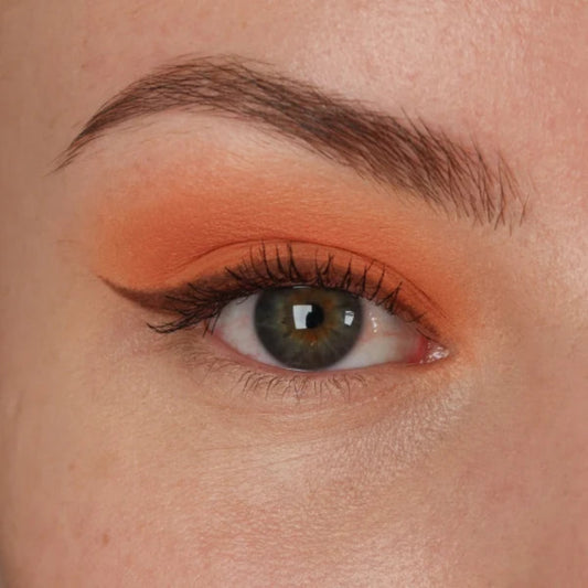 Nærbilde av et øye med ferskenoransje øyenskygge og mørk eyeliner med vinge