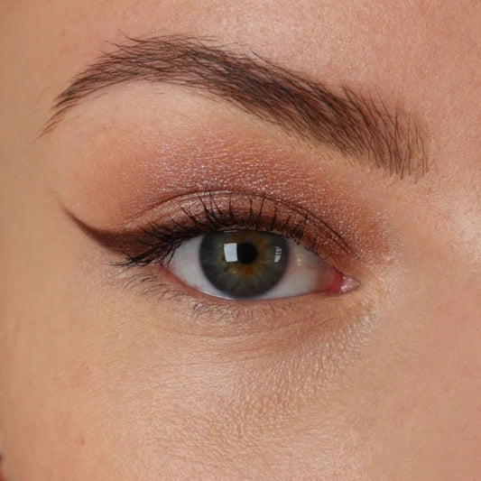 Nærbilde av et øye med skimrende rosébronse øyenskygge og mørk eyeliner med vinge