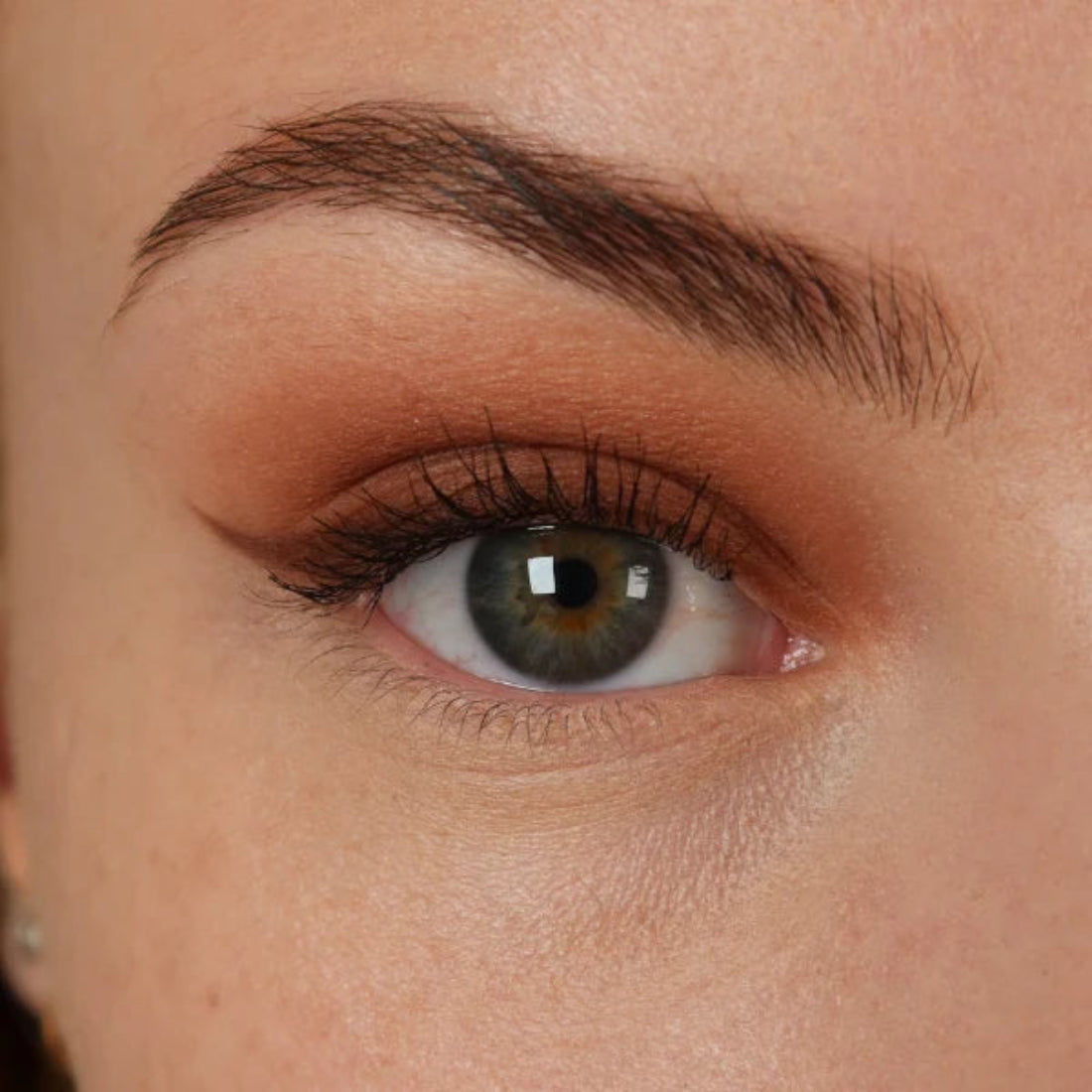 Nærbilde av et øye med varm karamellbrun øyenskygge og mørk eyeliner med vinge