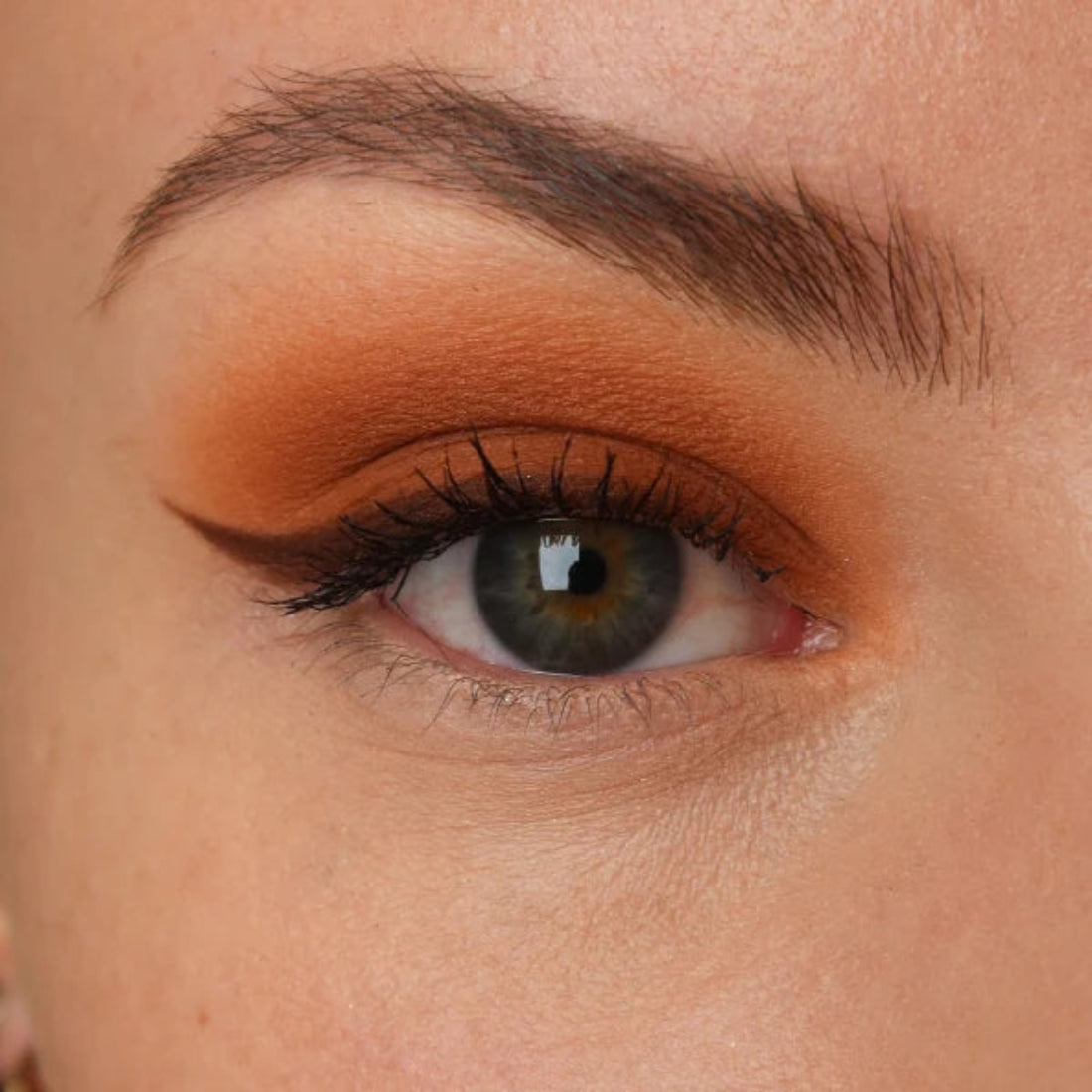 Nærbilde av et øye med varm kobberbrun øyenskygge og mørk eyeliner med vinge