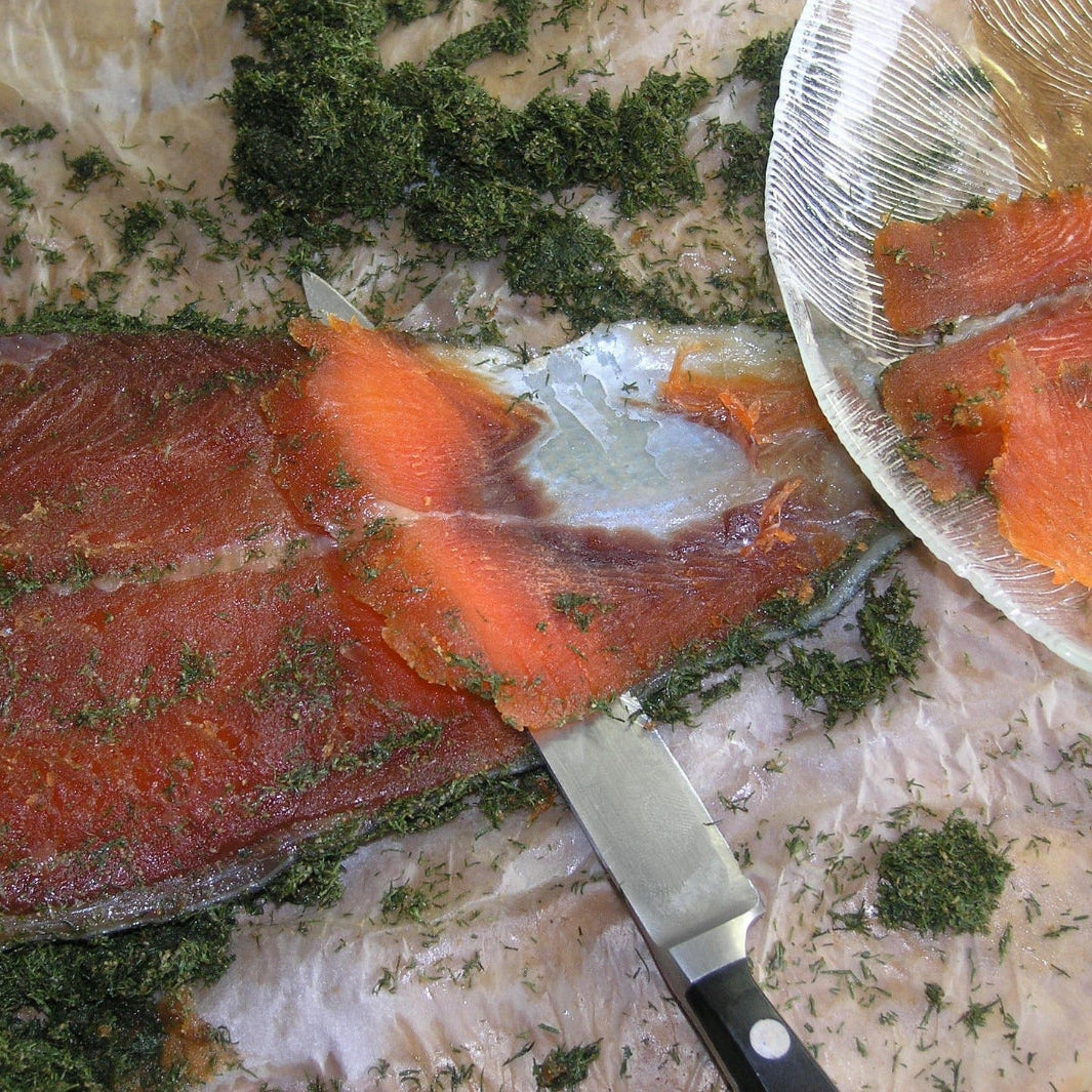 Fersk laksefilet med dill skjæres i skiver – laks er en naturlig kilde til omega-3 fettsyrene EPA og DHA, tilsvarende nøkkelfettsyrer som finnes i Herba Plus Cirkulan