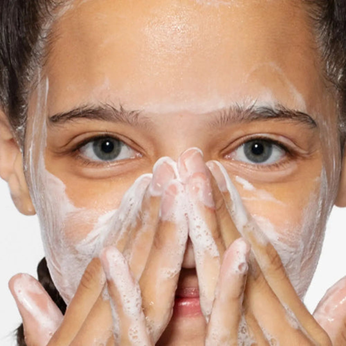 Kvinne som masserer Dermalogica Daily Microfoliant inn i fuktig hud – risbasert enzympulver for skånsom daglig eksfoliering, gir jevnere og lysere hud