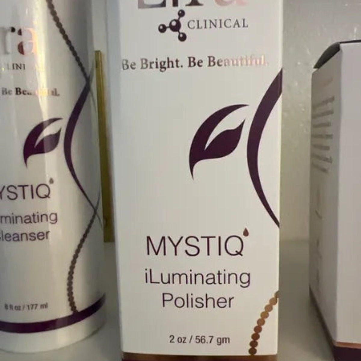 Lira Clinical MYSTIQ iLuminating Polisher produkteske – hvit og burgunder MYSTIQ iLuminating Polisher-eske med Lira Clinical-logo, lysnende skrubb og peeling med gull, sølv og plantestamceller, 56,7 g