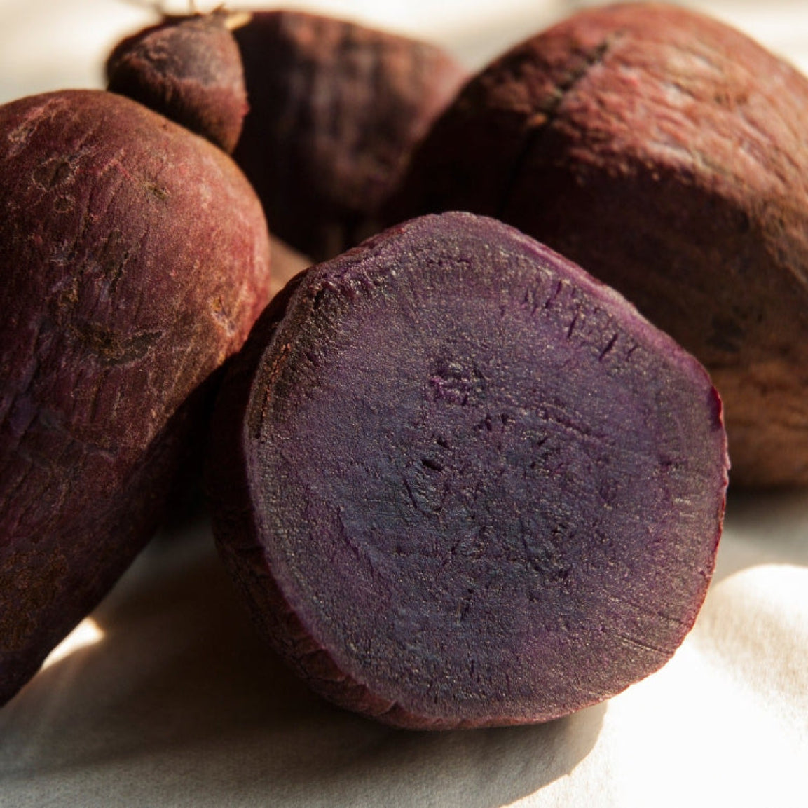 Mørkelilla yamsrøtter (Dioscorea) med en halvert rot som viser lilla innsiden – yamsrot er nøkkelingrediensen i Herba Plus Lady Plus, brukt i tradisjonell urtemedisin for hormonell balanse