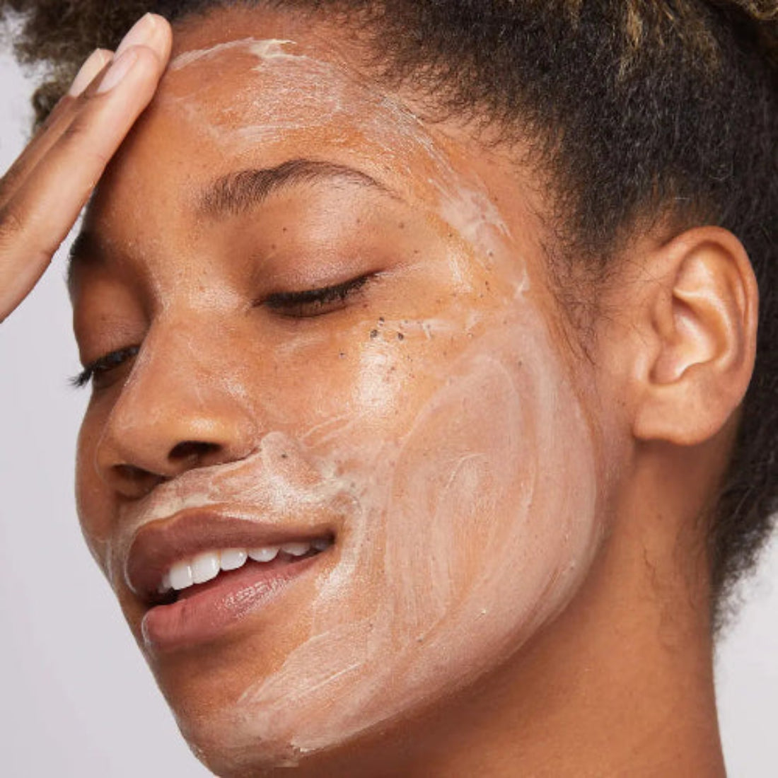 Smilende kvinne med Dermalogica MultiVitamin Power Recovery Masque påført ansiktet – bruk som 10-minutters kur eller over natten for ekstra dyp næring og gjenoppretting