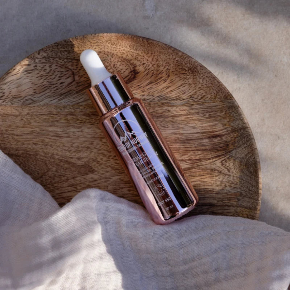Tind of Norway Norwegian Caviar serum merket Dry Skin på et rundt trefat ved siden av lyst stoff